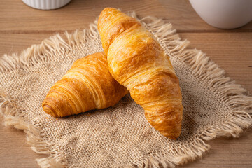 Freshly baked croissants resting on a textured cloth display at a bakery during the morning hours