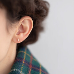 Fototapeta premium Close-up of Ear with Pearl Stud Earring and Plaid Fabric