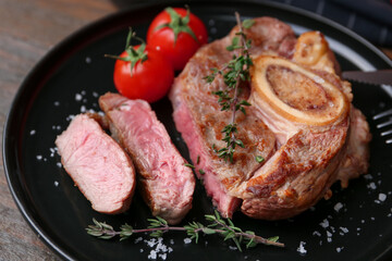 Pieces of delicious beef meat, spices and tomatoes on table, closeup