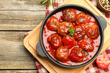 Delicious meatballs with tomato sauce in baking dish on wooden table, flat lay. Space for text