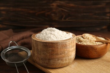 Brown rice, flour and sieve on wooden table, closeup