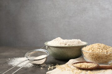 Brown rice, flour and sieve on grey table. Space for text