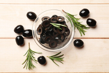Delicious marinated olive rings, whole ones and rosemary on light wooden table, flat lay