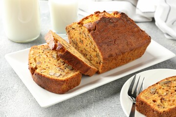 Cut homemade carrot cake with nuts and milk on grey table, closeup