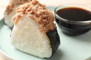 Tasty onigiri (Japanese rice balls) with tuna and soy sauce on table, closeup