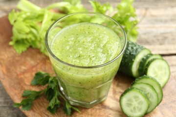 Healthy parsley smoothie in glass, leaves and cucumber on wooden table, closeup