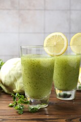 Healthy parsley drink in glasses, lemons and cabbage on wooden table, closeup