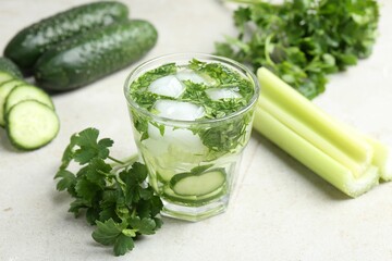 Healthy drink with parsley, cucumbers and celery on light table, closeup