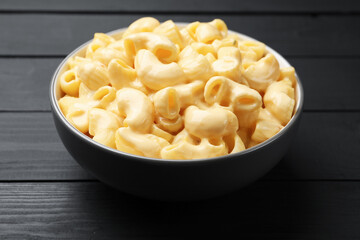 Delicious macaroni and cheese on black wooden table, closeup