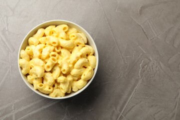 Delicious pasta with cheese sauce in bowl on grey table, top view. Space for text
