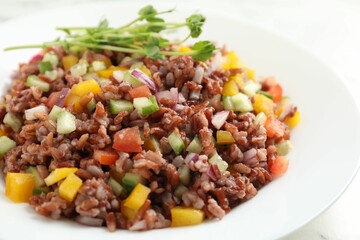 Tasty salad with brown rice on white table, closeup