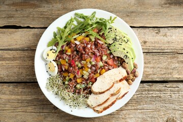 Tasty salad with brown rice on wooden table, top view