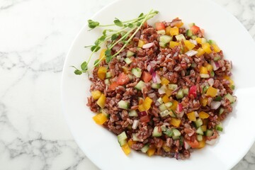 Tasty salad with brown rice on white marble table, top view