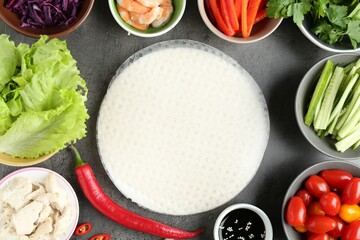 Rice paper sheets and different ingredients on dark grey table, flat lay