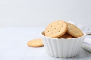 Tasty salty crackers on white tiled table, closeup. Space for text