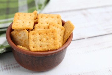 Tasty salty crackers on white wooden table, closeup