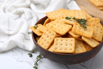 Tasty salty crackers and thyme on white table, closeup