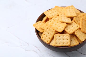 Tasty salty crackers on white textured table, closeup. Space for text