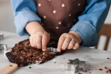 Cooking recipe. Little girl cutting cookie dough with cutters at table indoors, closeup