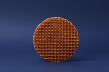 One tasty round waffle on blue background