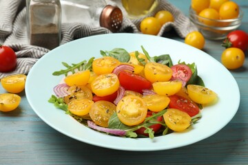 Fresh salad with yellow tomatoes served on light blue wooden table, closeup