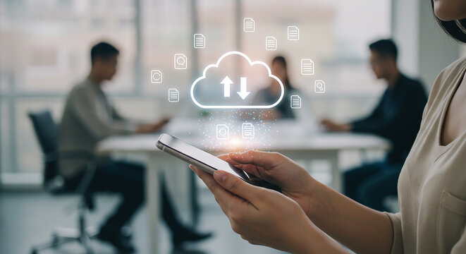 Woman using smartphone for cloud data transfer in office with colleagues at table in background