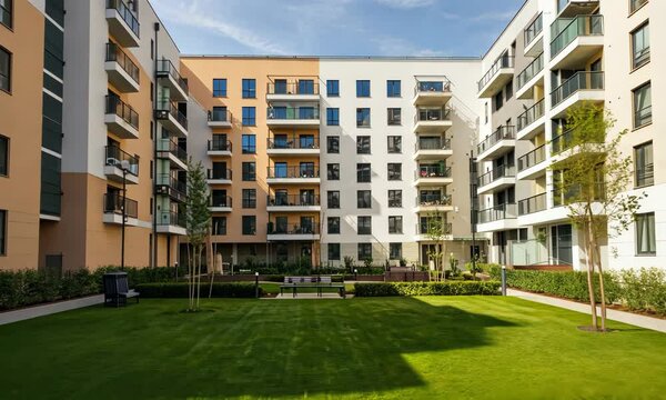 Modern apartment complex with courtyard, benches, and landscaping Bright sunny