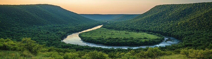 A captivating panoramic view of a winding river cutting through a vibrant green valley at dusk.