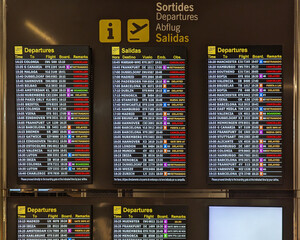 Digital airport departure boards screens showing flight cancellations and delays, destinations and boarding times at busy terminal. Schedule panel, extreme weather, delayed flights, waiting travel.