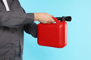 Man holding plastic canister on light blue background, closeup