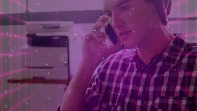man talking on smartphone by printer in tech office, displaying magenta grid and white speckles