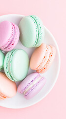 Obraz premium Pastel colored naturally dyed macarons on white plate for delicate dessert presentation