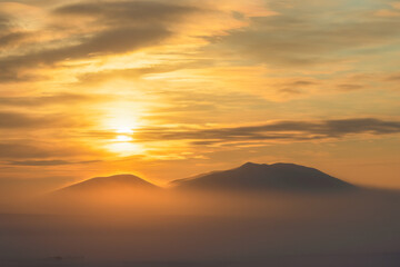 Beautiful sunset over the tundra and the snow-capped mountain. Winter arctic landscape. Cold frosty winter weather. Nature of Siberia and the Russian Far East. Chukotka, Far North of Russia, Arctic.