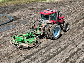 Red tractor using a liquid manure hose mover getting ready to assist in field opperations.