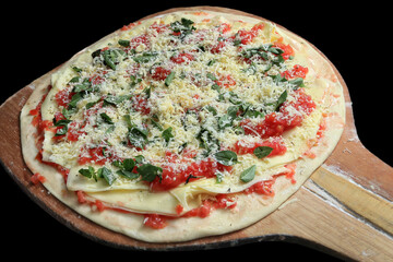 raw margherita pizza, assembled and prepared to be baked on a black background
