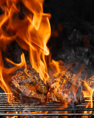 Two pieces of chicken are cooking on a grill, with flames