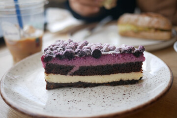 Chocolate and berry layered cake served with a drink at a cafe