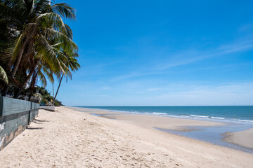 Cha-am Beach in Thailand, featuring a clean sandy shoreline, gentle waves, and a bright blue sky