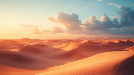 A desert landscape at sunset with orange-red sand dunes, clouds in the sky, and distant mountains illuminated by the setting sun.