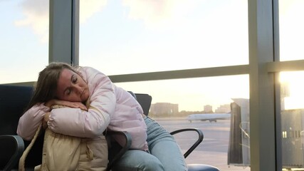 A young woman is comfortably resting on her bag at the airport, emphasizing the essence of travel fatigue and weariness