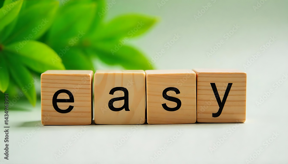 Fototapete wooden blocks spelling “easy” with green leaves in the background, symbolizing simplicity and natura