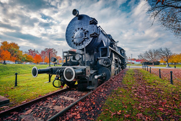 Exotic view of black olld train with steam locomotive in Bumbardo rail museum. Picturesque autumn cityscape of Hatvan town in Heves County, Hungary, Europe. Traveling concept background.