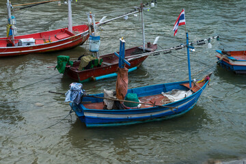 Obraz premium Wooden traditional fishing boats rest on the beach along the Thailand coast under a vast sky