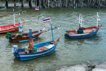 Wooden traditional fishing boats rest on the beach along the Thailand coast under a vast sky
