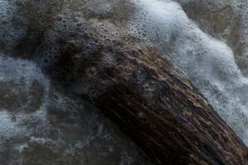 Fresh water flows over natural rocks, cascading into the flowing river in a vibrant summer landscape