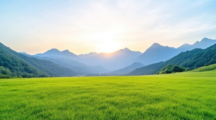 Fototapeta premium Lush green meadow stretches beneath majestic mountains at sunrise. A serene landscape of vibrant green grass, gently sloping hills, and distant mountain peaks bathed in the golden light of dawn.