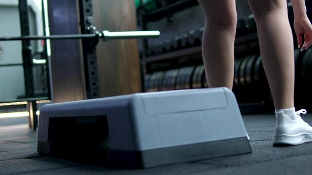 girl getting ready for step aerobics adjusting the device fits