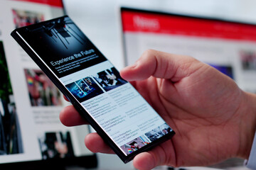 Watching Online News Article On Mobile Phone And Laptop