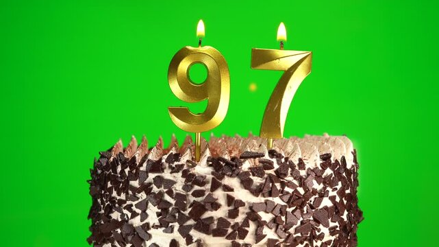 Burning candles number 97 on birthday cake against chroma key background. Ninety-seventh birthday. Birthday and anniversary celebration