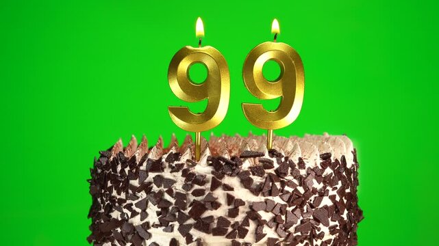 Burning candles number 99 on birthday cake against chroma key background. Ninety-ninth birthday. Birthday and anniversary celebration
